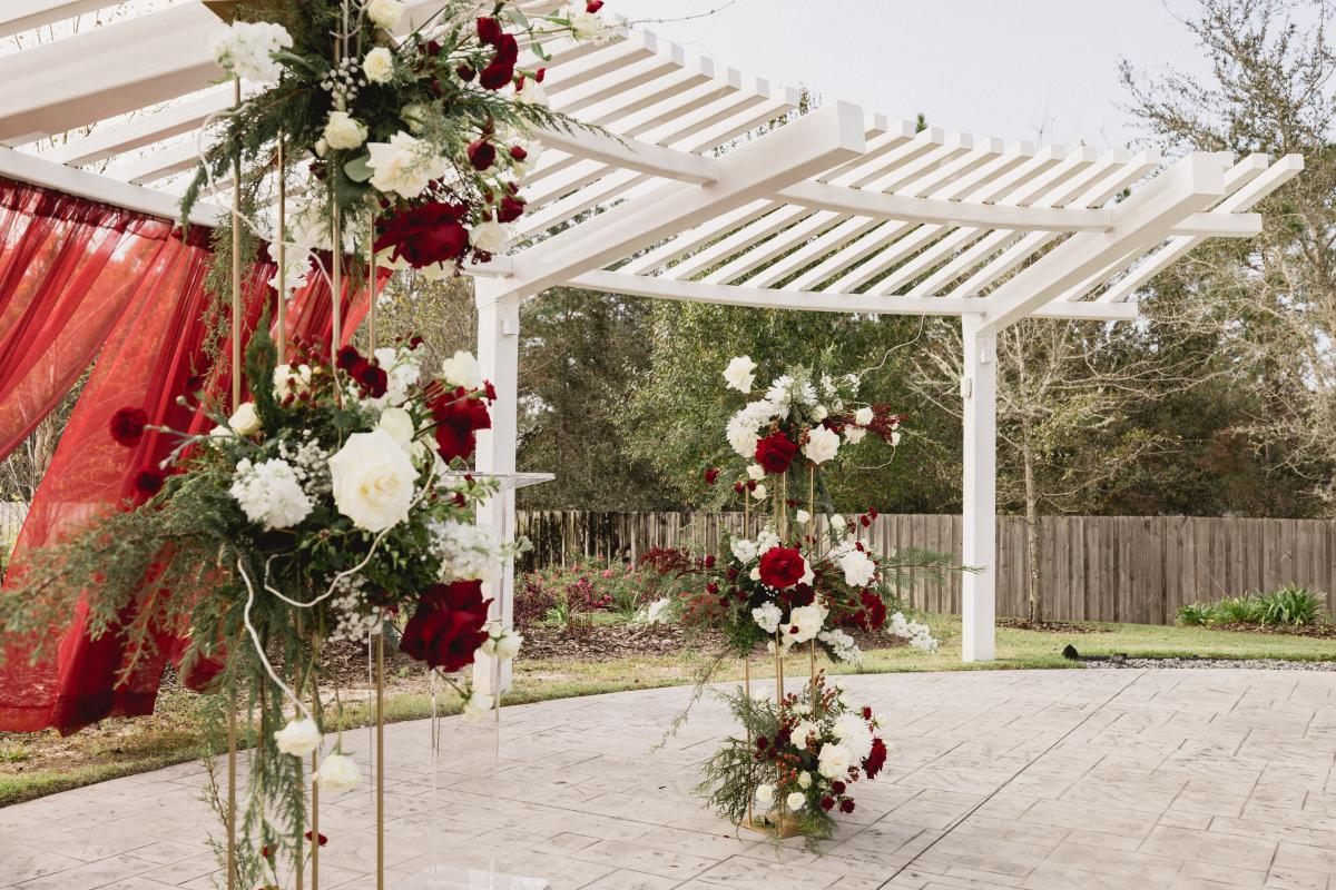 A Red Curtain and Flowers Decorate the Pergola